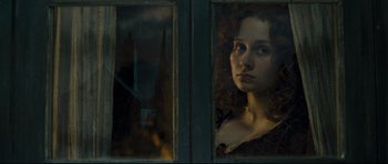 Movie still from “Oliver Twist” (2005), directed by Roman Polanski – A young woman looking out of a window at night; Close Up shot, Over the shoulder angle