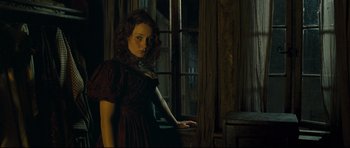 Movie still from “Oliver Twist” (2005), directed by Roman Polanski – A woman standing in front of a window in a dark room; Medium shot, Low angle