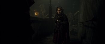 Movie still from “Oliver Twist” (2005), directed by Roman Polanski – A woman standing in the dark holding a knife; Medium shot, Over the shoulder angle