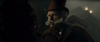 Movie still from “Oliver Twist” (2005), directed by Roman Polanski – An old man with a mustache wearing a top hat; Close Up shot, Over the shoulder angle
