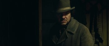 Movie still from “Oliver Twist” (2005), directed by Roman Polanski – A man wearing a hat and a trench coat in the dark; Close Up shot, Over the shoulder angle