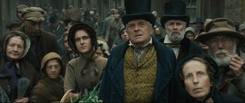 Movie still from “Oliver Twist” (2005), directed by Roman Polanski – A group of people standing next to each other in a crowd; Medium shot, Low angle