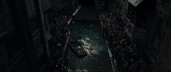 Movie still from “Oliver Twist” (2005), directed by Roman Polanski – A crowd of people standing next to a boat in water; Extreme Wide shot, Overhead angle