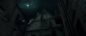 Movie still from “Oliver Twist” (2005), directed by Roman Polanski – A man hanging from a crane in front of a building; Wide shot, Low angle