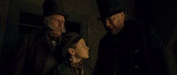 Movie still from “Oliver Twist” (2005), directed by Roman Polanski – Two men and a boy wearing hats and a top hat; Medium shot, Over the shoulder angle