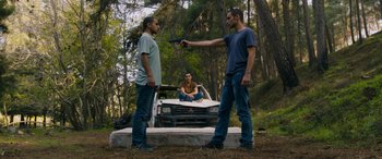 Movie still from “Omar” (2013), directed by Hany Abu-Assad – Two men stand in front of a truck while another man holds a gun pointed at them; Wide shot, Low angle
