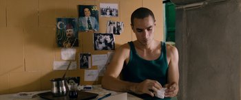 Movie still from “Omar” (2013), directed by Hany Abu-Assad – A man sitting at a table with a cup in his hand; Medium shot, Over the shoulder angle