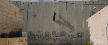 Movie still from “Omar” (2013), directed by Hany Abu-Assad – A man standing on top of a cement wall; Extreme Wide shot, Overhead angle