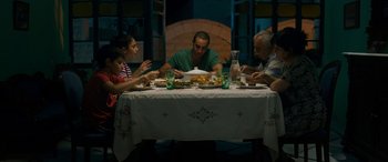 Movie still from “Omar” (2013), directed by Hany Abu-Assad – A group of people sitting around a table eating; Wide shot, High angle