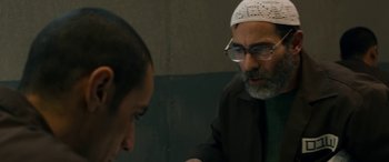 Movie still from “Omar” (2013), directed by Hany Abu-Assad – A man with a beard and glasses talking to another man; Close Up shot, Over the shoulder angle