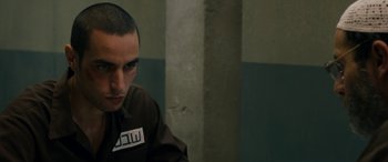 Movie still from “Omar” (2013), directed by Hany Abu-Assad – A man in a brown shirt is looking at the camera; Close Up shot, Over the shoulder angle