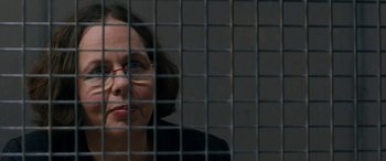 Movie still from “Omar” (2013), directed by Hany Abu-Assad – A woman with glasses is behind a metal fence; Close Up shot, Over the shoulder angle