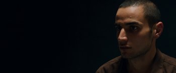 Movie still from “Omar” (2013), directed by Hany Abu-Assad – A person's face in a dark room; Close Up shot, Low angle