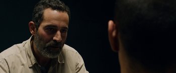 Movie still from “Omar” (2013), directed by Hany Abu-Assad – A man sitting in front of another man in front of a black background; Close Up shot, Over the shoulder angle