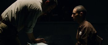 Movie still from “Omar” (2013), directed by Hany Abu-Assad – Two men are looking at a table in a dark room; Medium shot, Over the shoulder angle