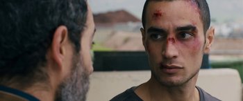 Movie still from “Omar” (2013), directed by Hany Abu-Assad – A man with blood all over his face stares at another man with blood all over his face; Close Up shot, Over the shoulder angle