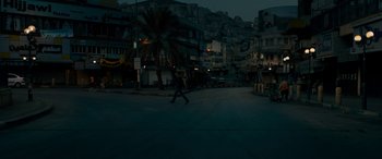 Movie still from “Omar” (2013), directed by Hany Abu-Assad – A person walking across a street at night; Extreme Wide shot, High angle