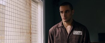 Movie still from “Omar” (2013), directed by Hany Abu-Assad – A man standing in front of a window looking to his left; Close Up shot, Over the shoulder angle