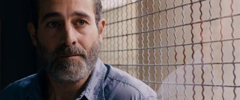 Movie still from “Omar” (2013), directed by Hany Abu-Assad – A person with a beard near a fence; Close Up shot, Over the shoulder angle