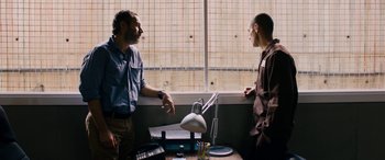 Movie still from “Omar” (2013), directed by Hany Abu-Assad – Two men are standing in front of a window; Medium shot, Over the shoulder angle