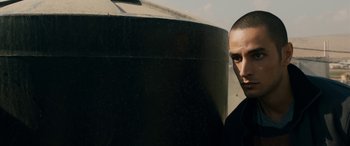 Movie still from “Omar” (2013), directed by Hany Abu-Assad – A man standing in front of a water tank; Close Up shot, Low angle