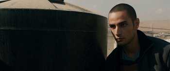 Movie still from “Omar” (2013), directed by Hany Abu-Assad – A man standing next to a water tank; Close Up shot, Low angle
