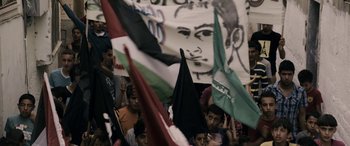 Movie still from “Omar” (2013), directed by Hany Abu-Assad – A group of people holding up flags and banners; Medium shot, High angle