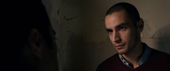 Movie still from “Omar” (2013), directed by Hany Abu-Assad – A man with a bald head and a dark background; Close Up shot, Low angle