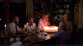 Movie still from “On Golden Pond” (1981), directed by Mark Rydell – A group of people sitting around a table with a cake; Medium shot, High angle