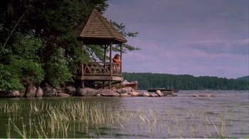Movie still from “On Golden Pond” (1981), directed by Mark Rydell – A woman sitting on a wooden gazebo on the shore of a lake; Extreme Wide shot, Low angle