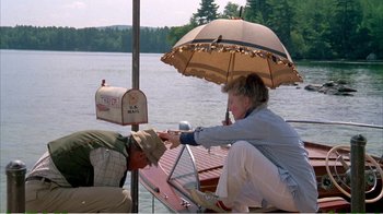 Movie still from “On Golden Pond” (1981), directed by Mark Rydell – A man and a woman sitting on a boat under an umbrella; Wide shot, High angle