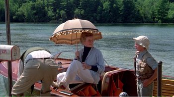 Movie still from “On Golden Pond” (1981), directed by Mark Rydell – An older woman sitting on a boat holding an umbrella; Wide shot, Over the shoulder angle