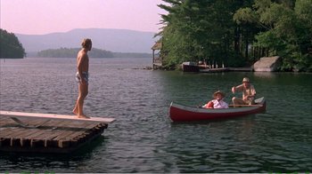 Movie still from “On Golden Pond” (1981), directed by Mark Rydell – A woman standing on a dock next to a canoe; Wide shot, High angle