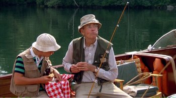 Movie still from “On Golden Pond” (1981), directed by Mark Rydell – An older man sitting on a boat with a young boy; Medium shot, Low angle