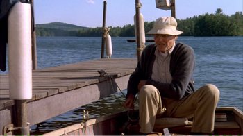 Movie still from “On Golden Pond” (1981), directed by Mark Rydell – An older man sitting on a boat on the water; Wide shot, High angle