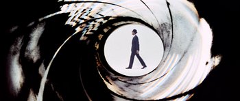 Movie still from “On Her Majesty's Secret Service” (1969), directed by Peter R. Hunt – A man in a fedora walking through a gun barrel; Extreme Close Up shot, Low angle