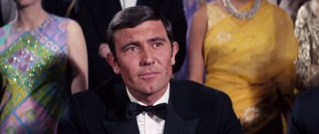 Movie still from “On Her Majesty's Secret Service” (1969), directed by Peter R. Hunt – A person wearing a suit and bow tie; Close Up shot, Low angle