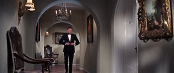 Movie still from “On Her Majesty's Secret Service” (1969), directed by Peter R. Hunt – A man in a tuxedo standing in a hallway; Wide shot, Low angle