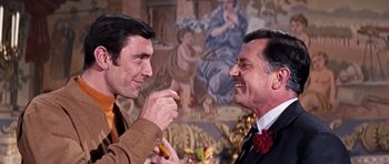 Movie still from “On Her Majesty's Secret Service” (1969), directed by Peter R. Hunt – A couple of men standing next to each other; Medium shot, Over the shoulder angle