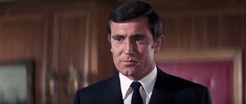 Movie still from “On Her Majesty's Secret Service” (1969), directed by Peter R. Hunt – A man in a suit and tie; Close Up shot, Low angle