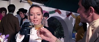 Movie still from “On Her Majesty's Secret Service” (1969), directed by Peter R. Hunt – A woman holding up a glass of champagne; Close Up shot, Low angle