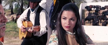Movie still from “On Her Majesty's Secret Service” (1969), directed by Peter R. Hunt – A woman with long black hair is playing a guitar; Close Up shot, Low angle