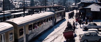 Movie still from “On Her Majesty's Secret Service” (1969), directed by Peter R. Hunt – People are riding on the side of a train on a snowy day; Extreme Wide shot, High angle