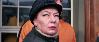Movie still from “On Her Majesty's Secret Service” (1969), directed by Peter R. Hunt – An older woman wearing a black hat and a black jacket; Close Up shot, Low angle