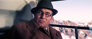 Movie still from “On Her Majesty's Secret Service” (1969), directed by Peter R. Hunt – A man wearing a hat and glasses sitting in a bus; Close Up shot, Low angle