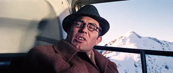 Movie still from “On Her Majesty's Secret Service” (1969), directed by Peter R. Hunt – A man in a hat and glasses riding a bus; Close Up shot, Low angle