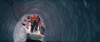 Movie still from “On Her Majesty's Secret Service” (1969), directed by Peter R. Hunt – A group of people walking down a ramp in a tunnel; Wide shot, High angle
