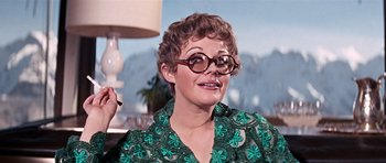 Movie still from “On Her Majesty's Secret Service” (1969), directed by Peter R. Hunt – A woman wearing glasses and a green shirt; Close Up shot, Low angle