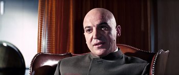 Movie still from “On Her Majesty's Secret Service” (1969), directed by Peter R. Hunt – A man with bald head sitting in a chair; Close Up shot, Low angle