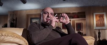 Movie still from “On Her Majesty's Secret Service” (1969), directed by Peter R. Hunt – A man smoking a cigarette while holding a cell phone; Medium shot, Low angle